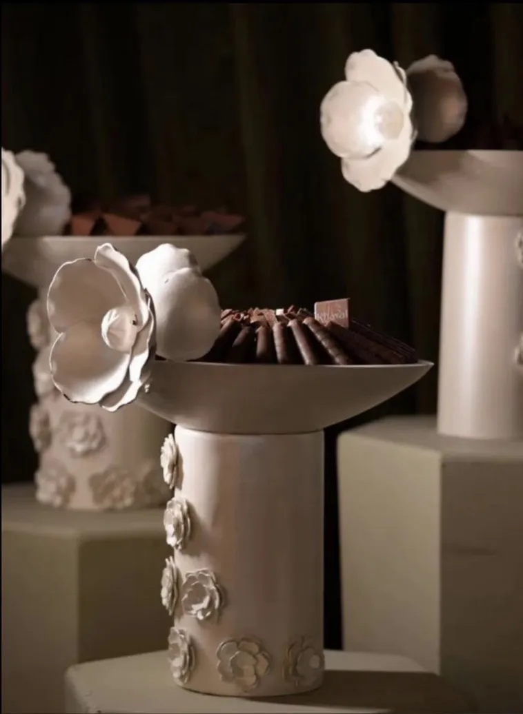 A dessert corner on white stands decorated with flowers