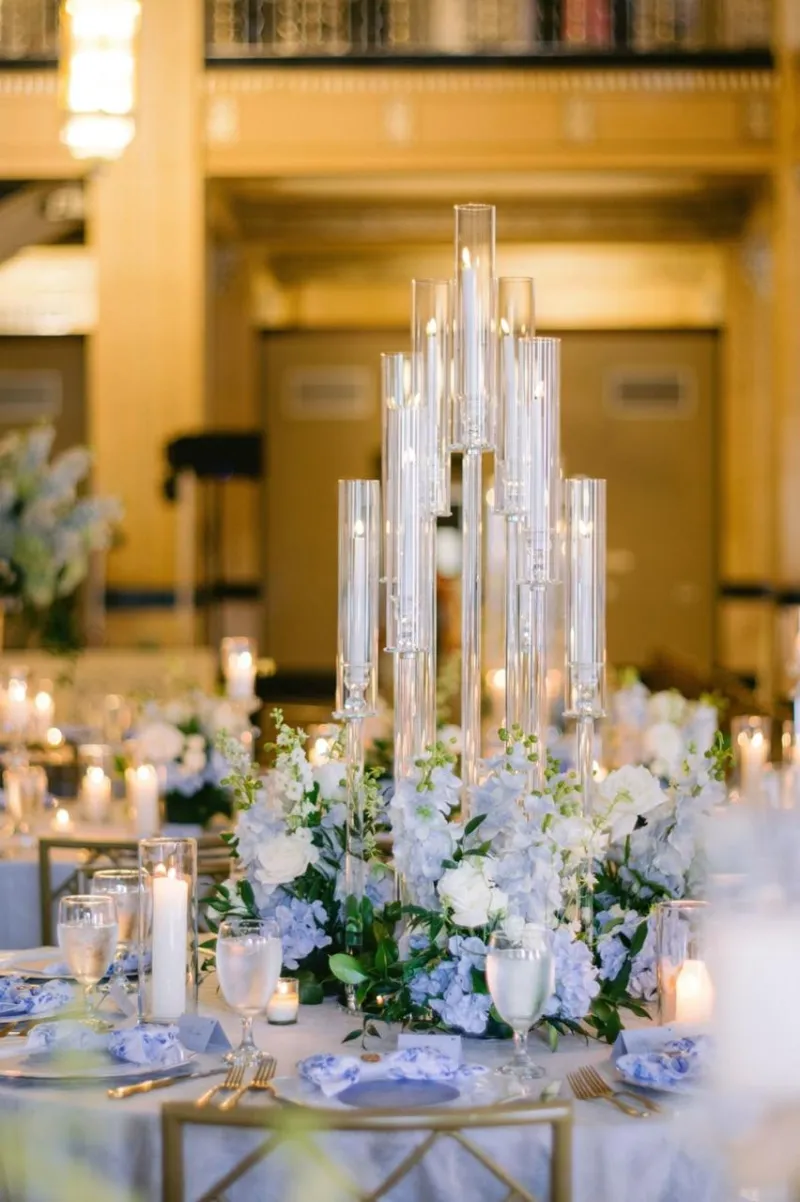 A centerpiece of tall glass candle holders with blue and white flowers