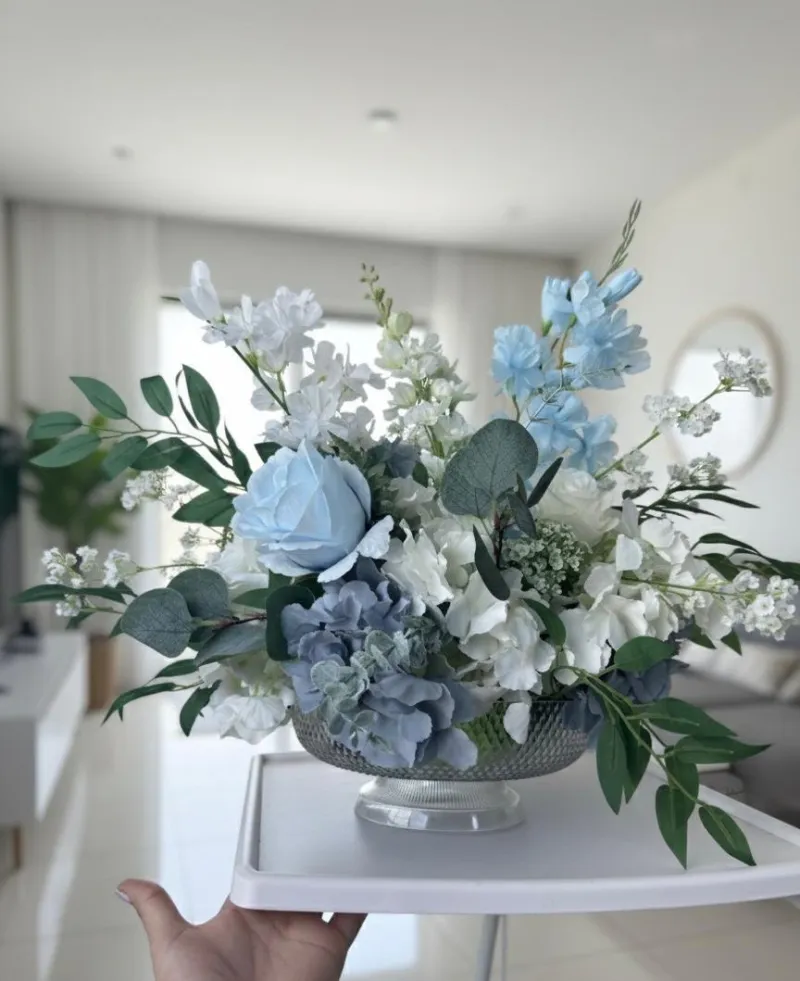 A blue and white floral arrangement in a crystal bowl