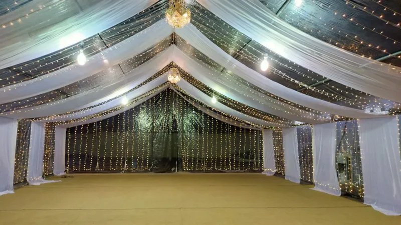 A tent with white drapes and curtain lights