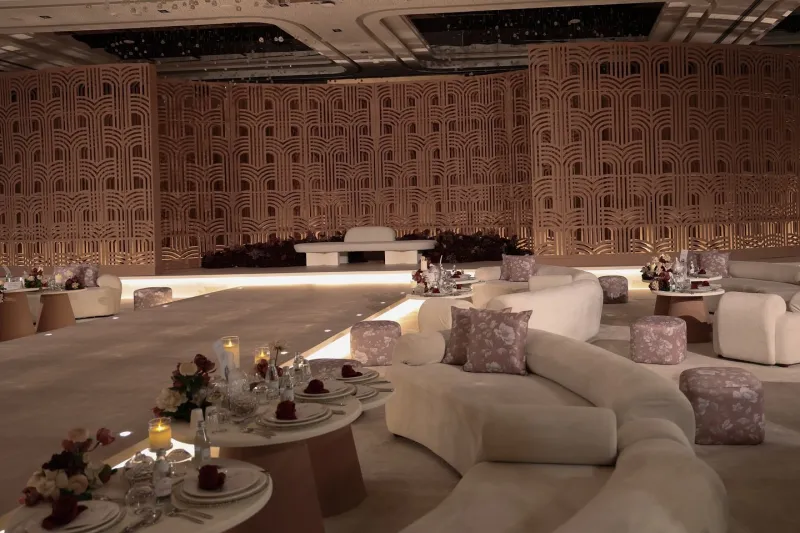 Curved lounges with pink cushions before a carved timber wall
