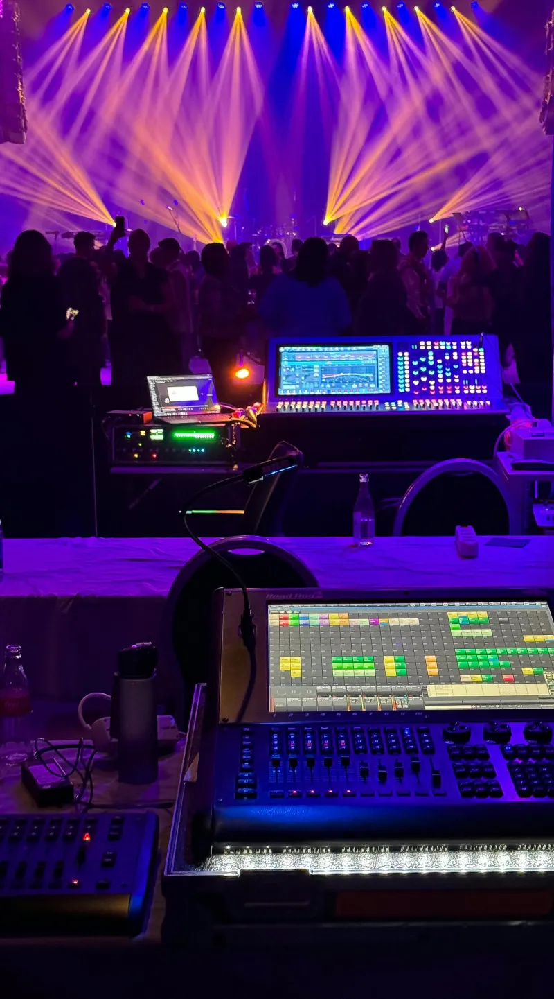 Lighting desks and purple and gold moving-head beams over the dance floor