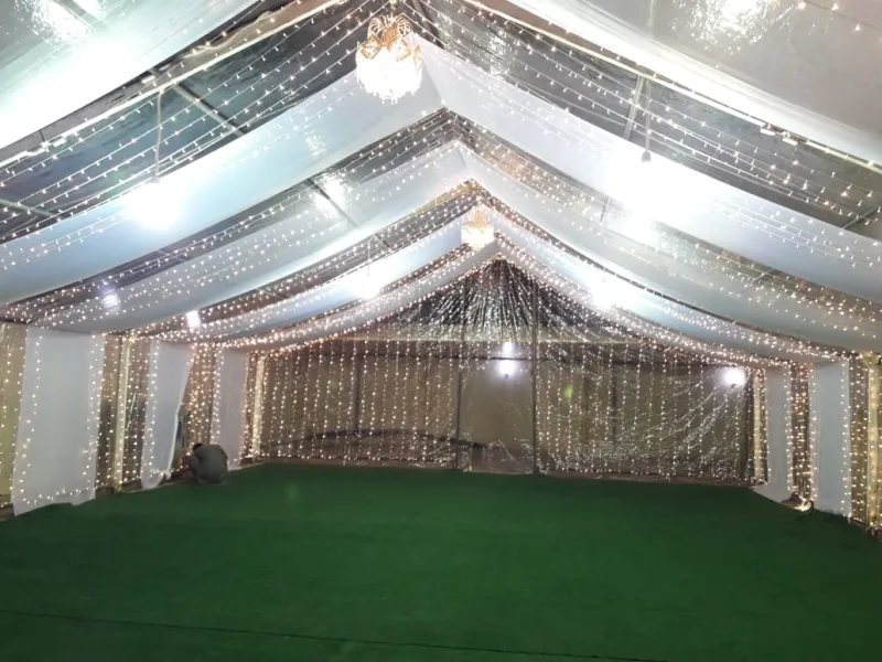 A tent with white swagged drapes and starlights on green turf