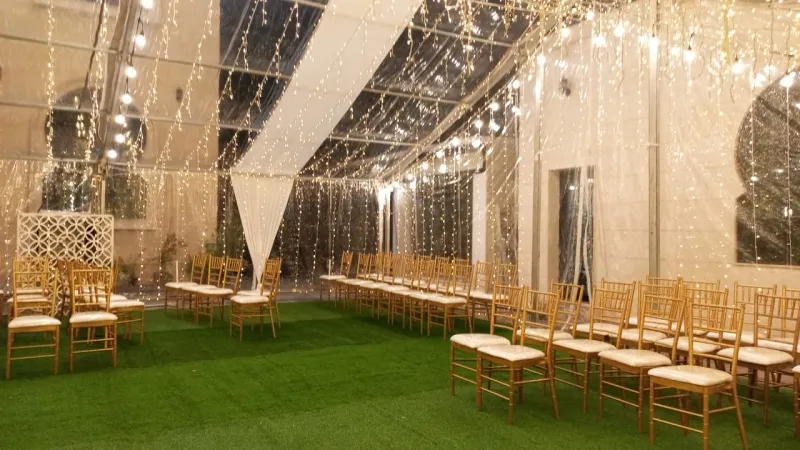 Gold Chiavari chairs on turf inside a lit tent