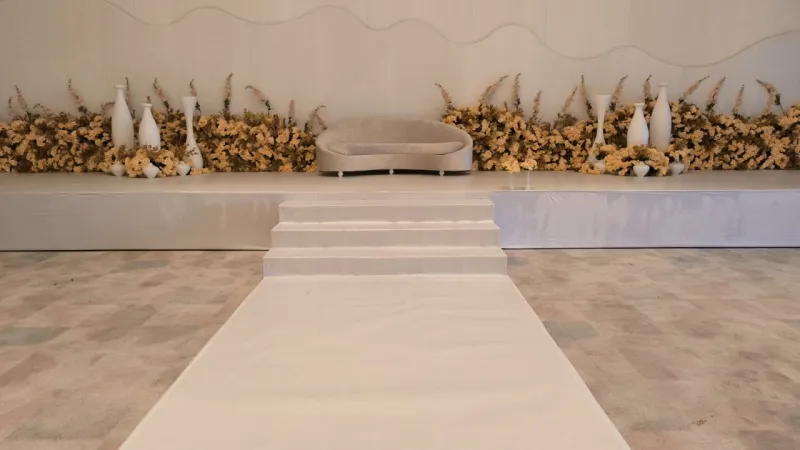 A white stage with steps, dried florals and a bridal sofa