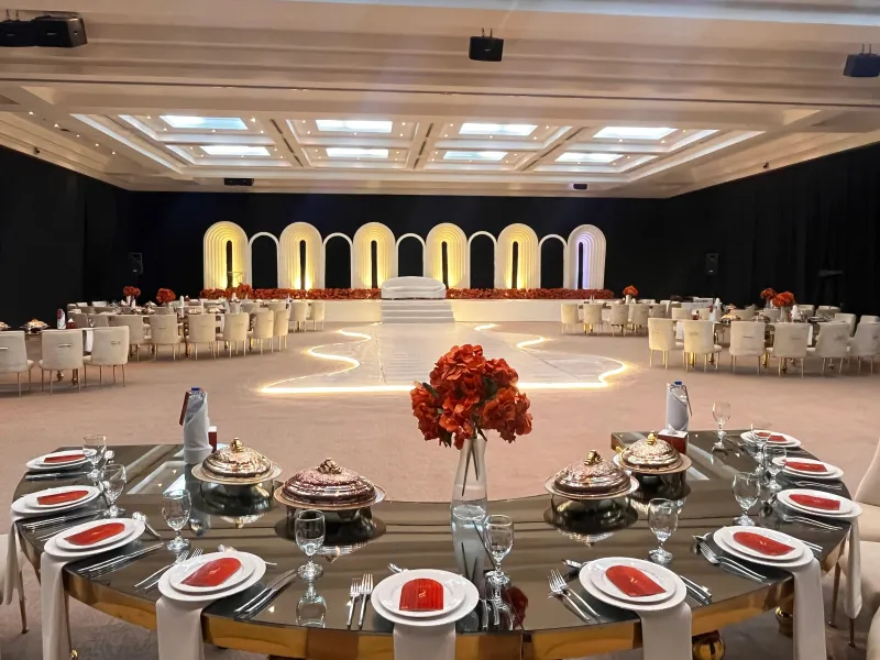 A gold reception table with red place settings and glowing arches behind